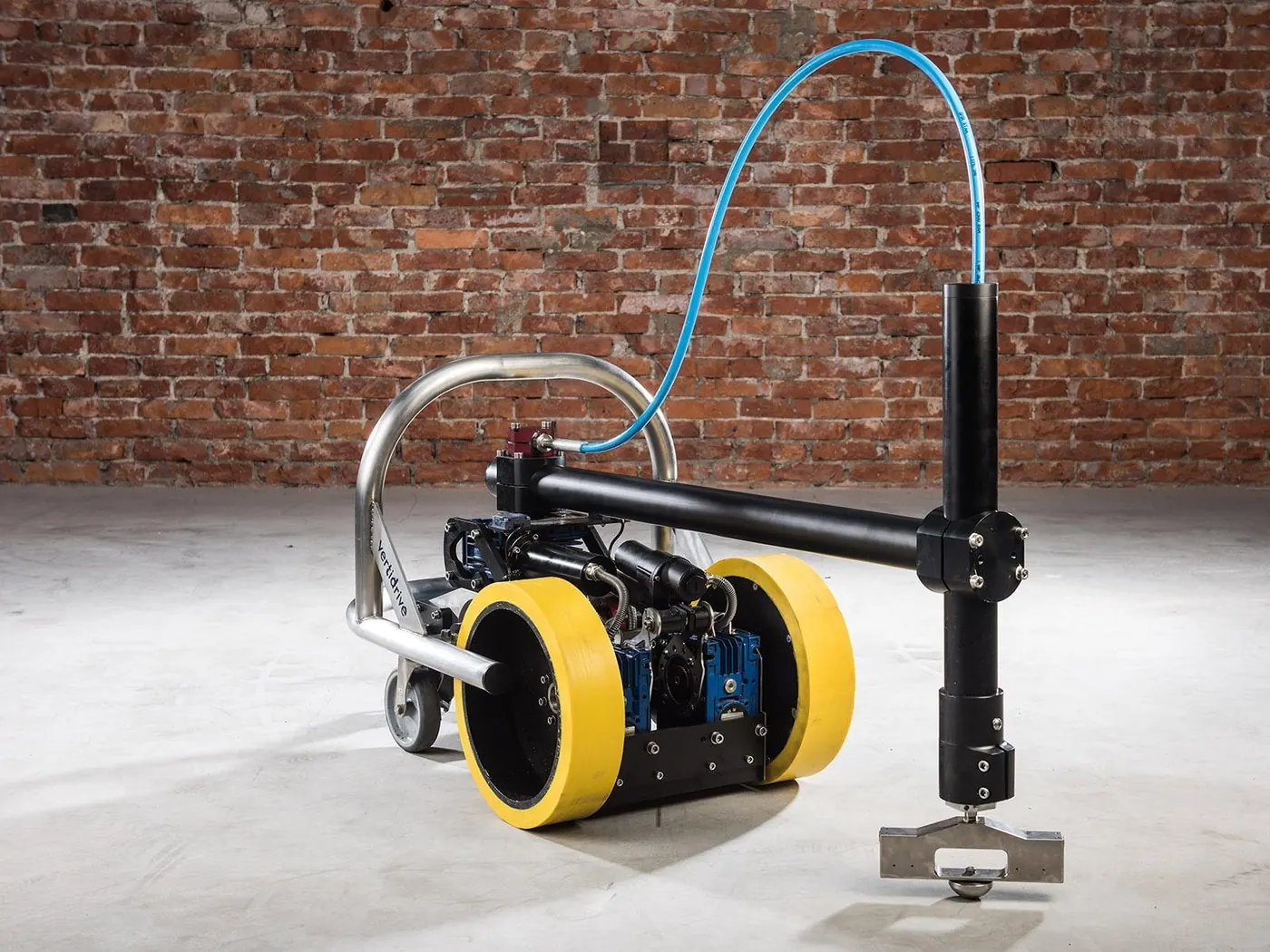 Robot à deux roues jaunes équipé d’un bras articulé et d’un flexible bleu, photographié en atelier